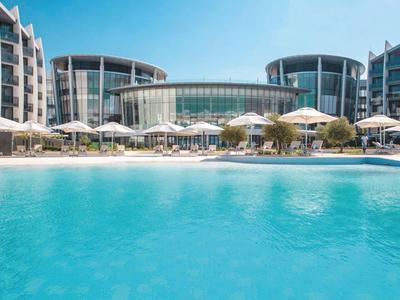 Complexe hôtelier moderne avec grande piscine extérieure et parasols sous ciel bleu