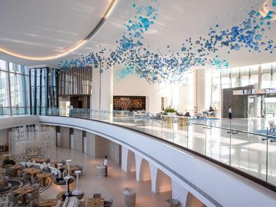 Großer, heller Hotel-Lobbybereich mit modernen Möbeln und blauer Deckendekoration.