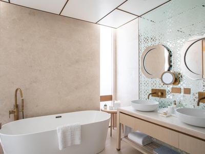 Salle de bain moderne avec baignoire autonome, doubles vasques et grand miroir.