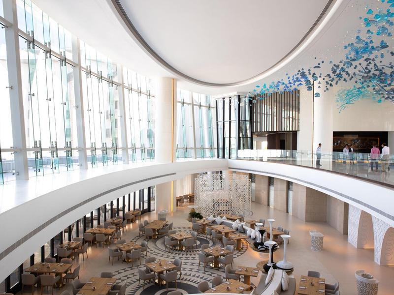 Grand hall d'hôtel moderne avec de grandes fenêtres et des espaces assis.