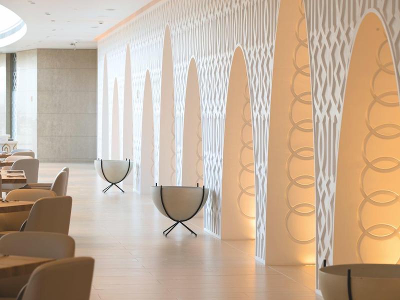 Espace salon d'hôtel lumineux avec fauteuils modernes et niches murales décoratives éclairées