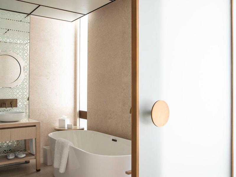 Salle de bain d'hôtel moderne avec baignoire îlot et lavabo avec miroir.