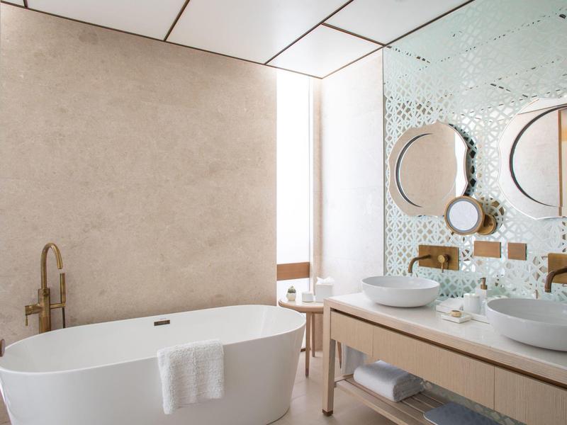 Salle de bain moderne avec baignoire autonome, doubles vasques et grand miroir.