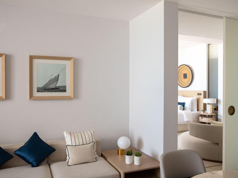 Espace salon confortable avec canapé, coussins et tableaux décoratifs au mur.