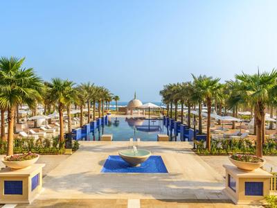 Luxuriöser Poolbereich mit Palmen und Blick auf das Meer in einem Hotelresort