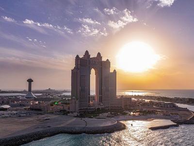 Coucher de soleil sur une ville côtière avec un grand bâtiment et des étendues d'eau.