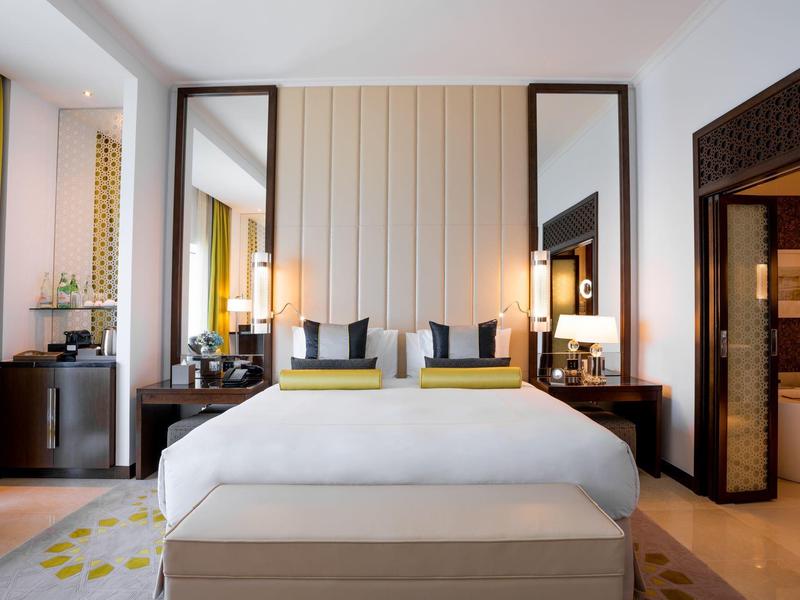 Chambre d'hôtel moderne avec grand lit, tables de chevet et lumière chaude.