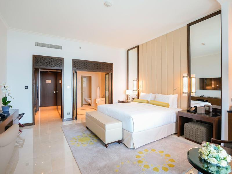 Chambre d'hôtel lumineuse avec grand lit, télévision et intérieur moderne et élégant.