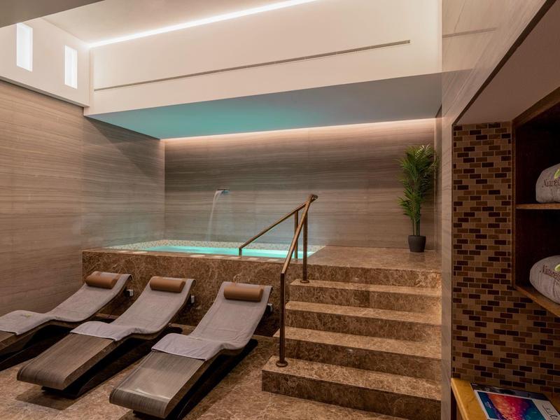 Espace bien-être moderne avec chaises longues et petite piscine aux tons chaleureux.