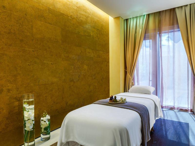 Studio de massage moderne avec deux tables de soin et lumière chaude sur le mur.