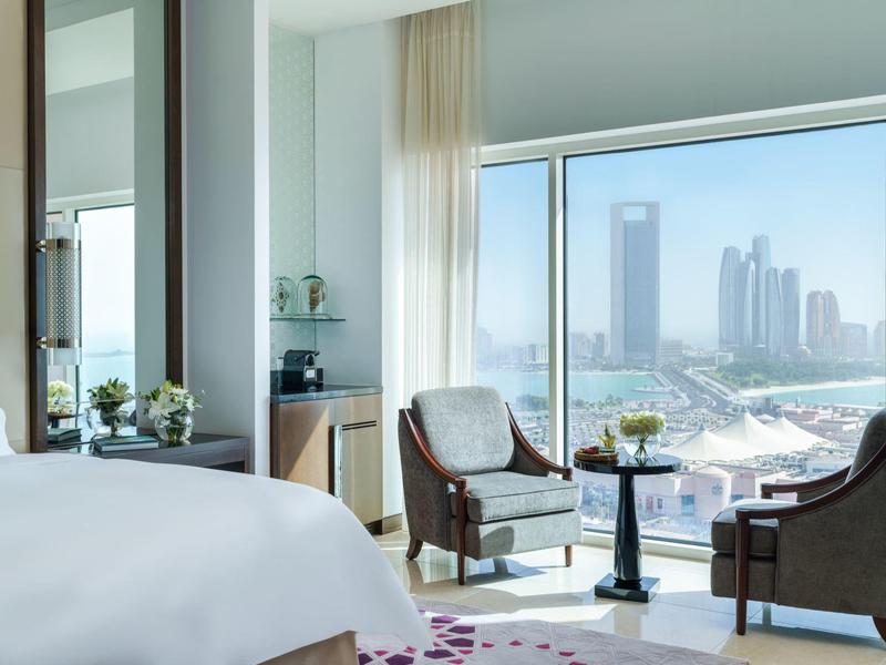 Chambre d'hôtel lumineuse avec une grande fenêtre offrant une vue sur la ville et les gratte-ciel.