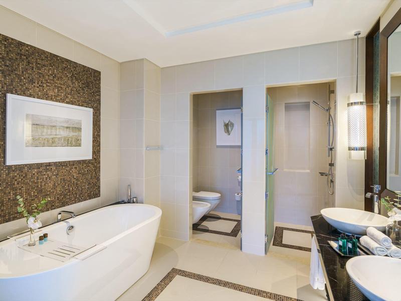 Salle de bain lumineuse avec baignoire îlot, double lavabo et décoration moderne.