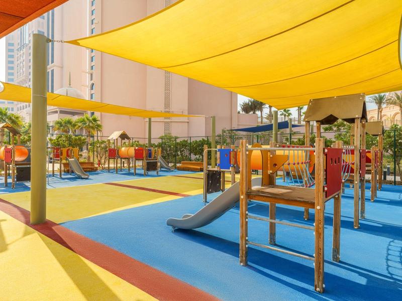 Aire de jeux colorée avec toboggans et voiles d'ombrage en milieu urbain