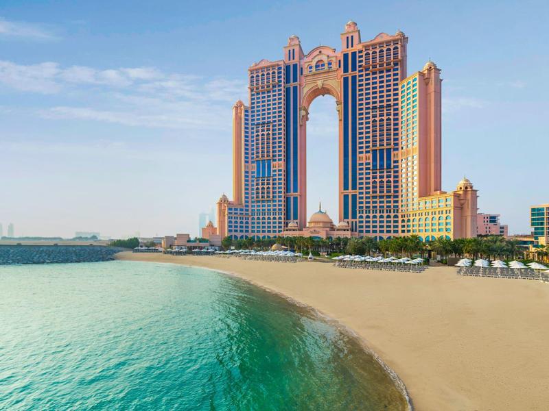 Hôtel moderne avec hautes tours sur une plage de sable et mer bleue claire sous un ciel bleu