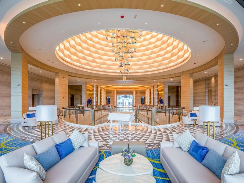 Lobby d'hôtel lumineuse avec éclairage de plafond élégant et espaces assis confortables.