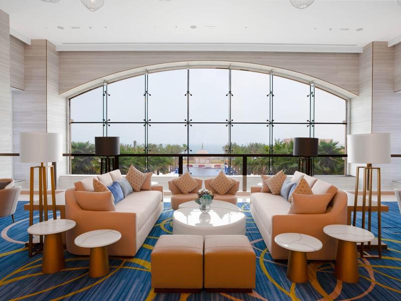 Hall d'hôtel lumineux avec grandes fenêtres, canapés confortables et sièges modernes.