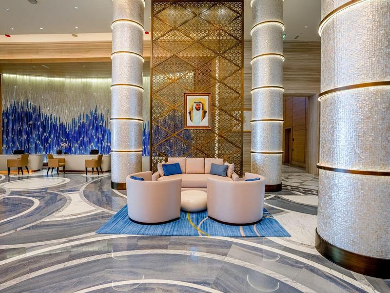 Hall d'hôtel élégant avec fauteuils ronds et sol en marbre bleu-gris.