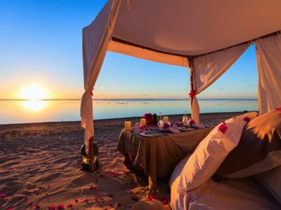 Lounge sulla spiaggia di lusso al tramonto con vista mare e posti a sedere accoglienti.