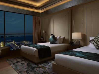 Luxusní hotelový pokoj se dvěma postelemi, velkým oknem a nočním osvětlením v noci.