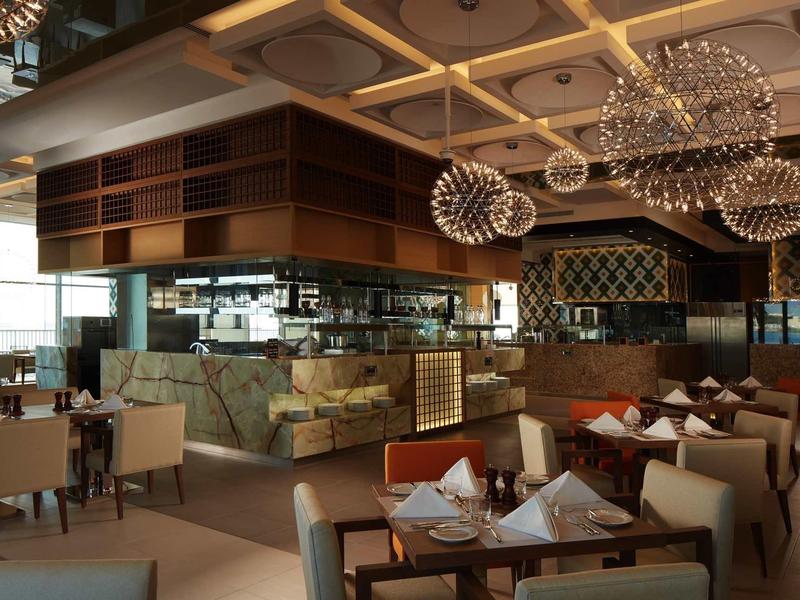 Moderní restaurace s elegantně prostřenými stoly a působivým osvětlením stropu.