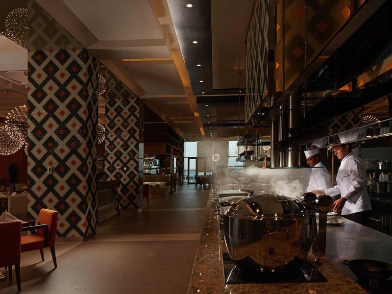 Stylová hotelová restaurace s elegantní atmosférou a kuchařem v otevřené kuchyni.