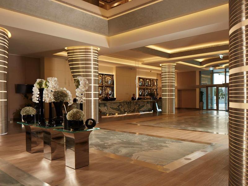 Elegantní hotelová lobby se osvětlenými sloupy a velkým kobercem.