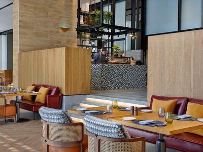 Moderní restaurace s dřevěným nábytkem, čalouněnými židlemi a teplou, příjemnou atmosférou.