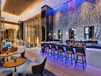 Moderner Hotelbarbereich mit stilvollen Sitzplätzen, großem Tresen und dekorativer Baumwandbeleuchtung.