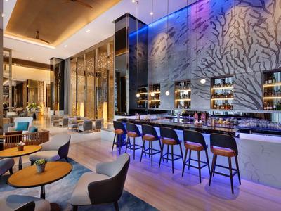 Moderní hotelový bar s stylovým posezením, dekorativní stěnou a atmosférickým osvětlením.