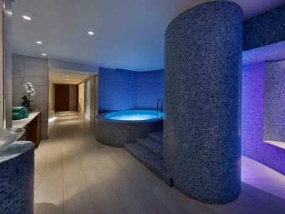 Moderner Wellnessbereich mit runden blauen Mosaikwänden, Whirlpool und sanfter Beleuchtung.