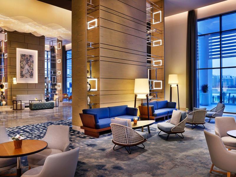 Modern hotel lounge area with seating groups, large windows, and stylish lighting.