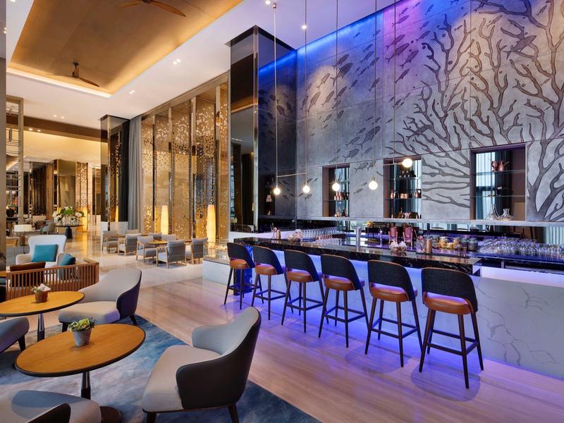 Modern hotel bar area with counter, bar stools, and stylish lighting.