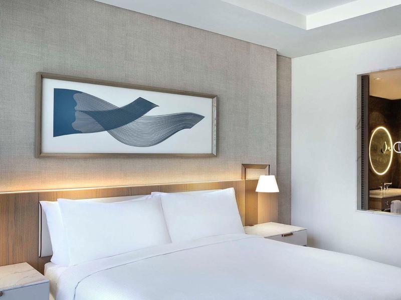 Modern hotel room with large double bed, stylish lighting, and contemporary bathroom.