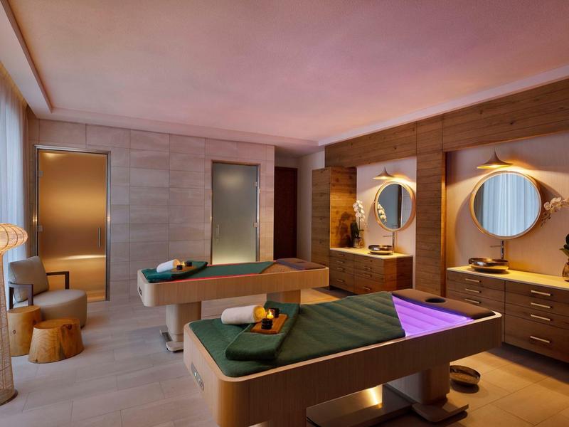 Modern wellness room with two massage tables and warm wood decor