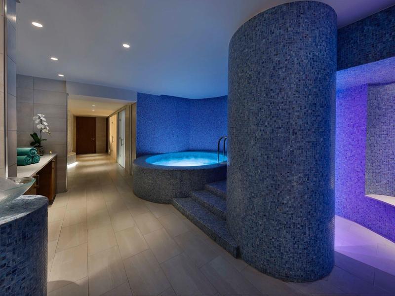 A modern spa area with a heated jacuzzi and blue ambient lighting.
