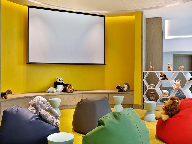 Modern cozy room with yellow wall, bean bags, and a large projector screen.