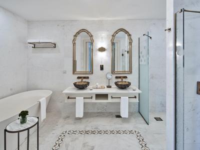 Baño elegante con bañera independiente, lavabo doble y ducha a ras de suelo.