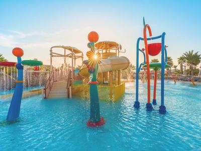 Parque acuático con toboganes coloridos y juegos bajo un cielo soleado y palmeras.