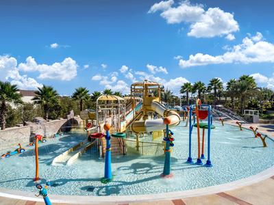 Zona de juegos acuáticos para niños con toboganes en un complejo vacacional bajo el sol.