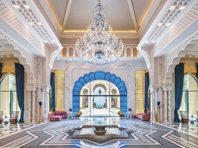 Lujoso vestíbulo de hotel con columnas magníficas, candelabro de cristal y diseño simétrico.