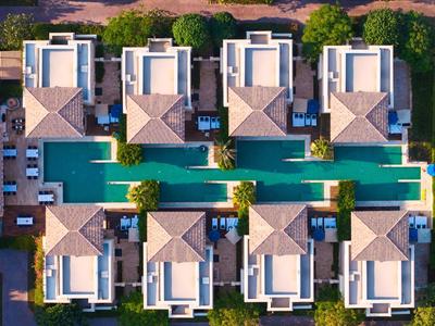 Symmetrische Wohnanlage mit modernen weißen Häusern und langem blauen Pool in der Mitte.