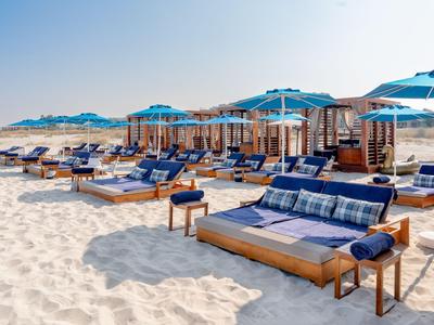 Plaża z leżakami i niebieskimi parasolami w słoneczny dzień