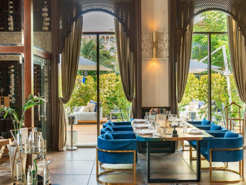 Interior elegante de restaurante con sillas azules y vista al jardín con sombrillas.
