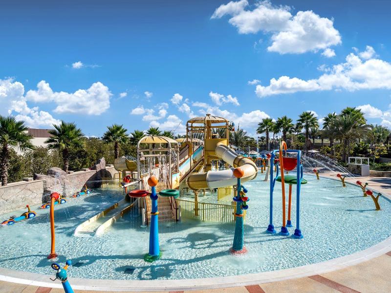 Zona de juegos acuáticos para niños con toboganes en un complejo vacacional bajo el sol.