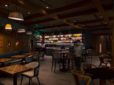 Dunkle Bar mit Holzmöbeln, Hockern, warmem Licht und einer beleuchteten Getränkeauswahl im Hintergrund.