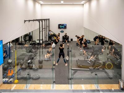Moderne fitnessruimte met glazen wanden, gewichten en mensen die trainen.