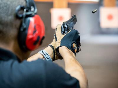 Persoon met gehoorbescherming schiet op een doel in een binnen schietbaan.