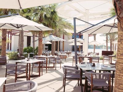 Elegante buitenruimte van een hotel met tafels, stoelen en grote parasols.