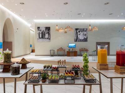 Buffetgedeelte van een modern hotel met verse sappen en kleine gerechten op tafels.