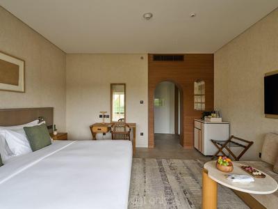 Modern eingerichtetes Hotelzimmer mit großem Bett, Schreibtisch, TV und Tisch mit Obstkorb.